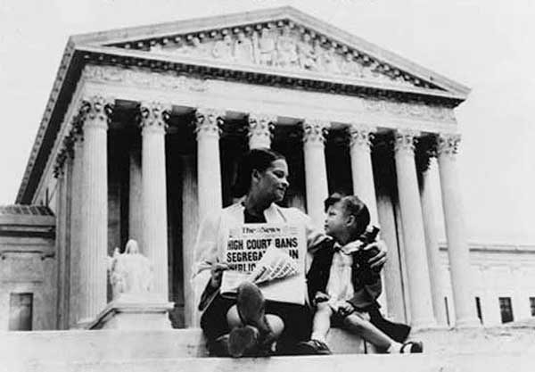 Mrs. Nettie Hunt, sitting on steps of Supreme Court, holding newspaper, explaining to her daughter Nikie the meaning of the Supreme Court's decision banning school segregation; photographed on the steps of the U.S. Supreme Court in Washington, D.C., November 19, 1954. New York World-Telegram & Sun Collection/Library of Congress, Washington, D.C. (LC-USZ62-127042)