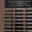 Wooden plaque with multiple black metal nameplates, "Outstanding Doctoral Student" heading on top nameplate, award winner names on three columns of smaller nameplates