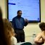 Professor Travis Albritton, dressed in a blue shirt and black pants, speaks to a classroom of new MSW students.