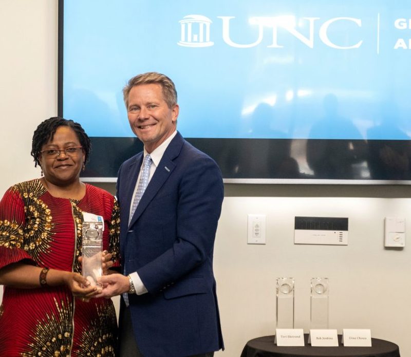 Gina Chowa, left, receives an award from UNC Chancellor Kevin Guskiewicz.