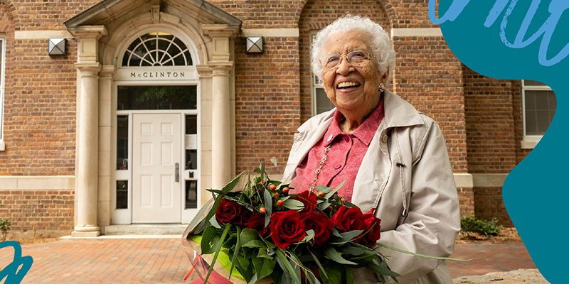 Photo of Hortense McClinton, for whom the Hortense McClinton Legacy Scholarship is named, holding flowers and smiling outside of the residence hall which also bears her name.