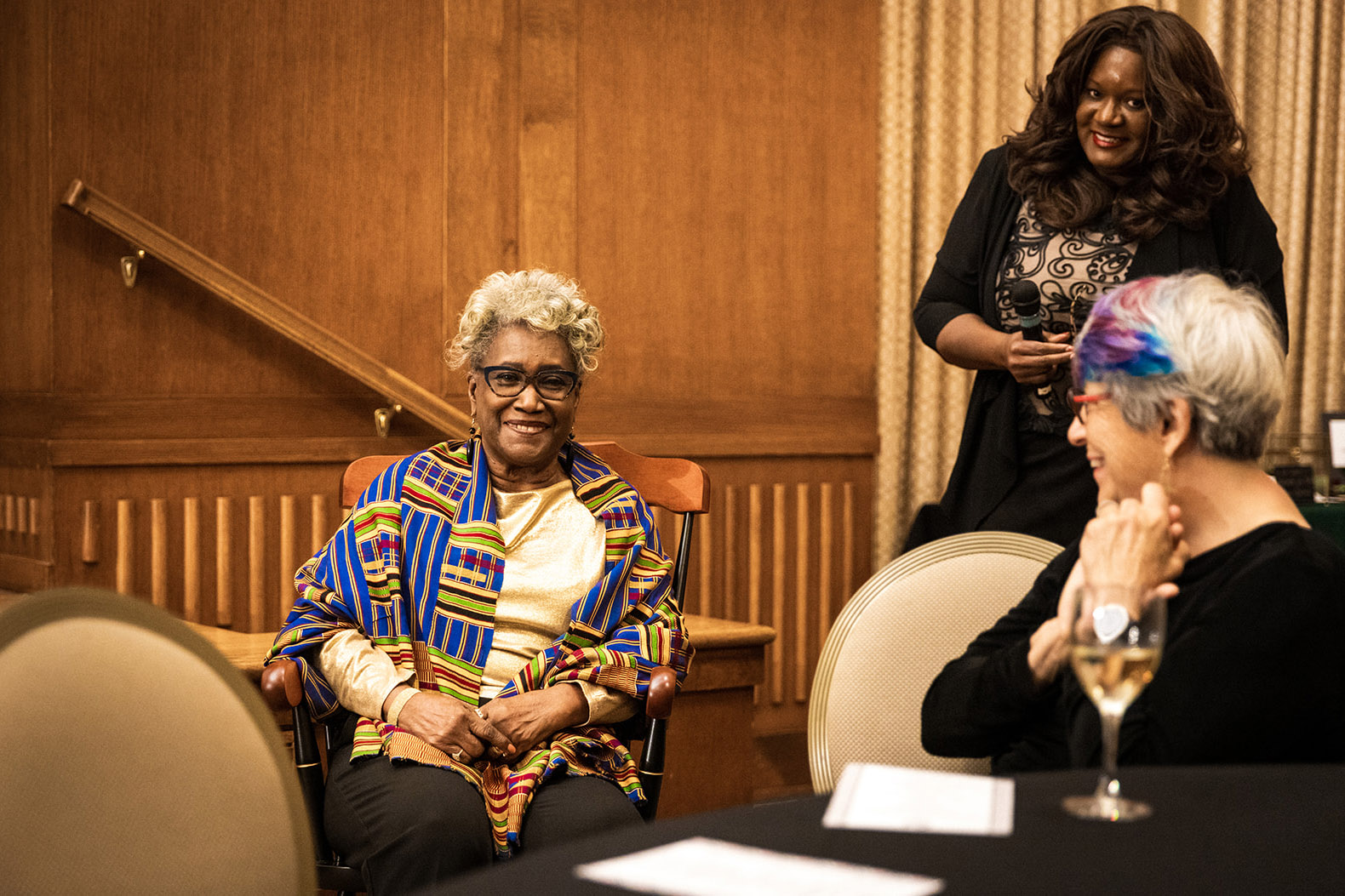 Iris Carlton-LaNey is presented a rocking chair during her retirement party by UNC School of Social Work Dean Ramona Dinby-Brenson.